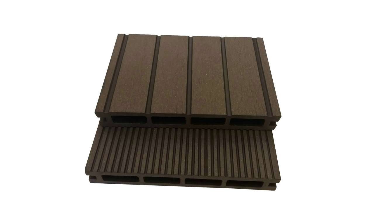 Overhead flat-lay photograph of two stacked dark brown composite decking boards, one grooved and one smooth, hollow chambers visible, on white background, soft top light, rich chocolate and mahogany tones with a calm material-sample mood.