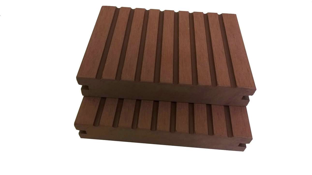 Overhead flat-lay of two stacked reddish-brown solid grooved composite deck boards on a white surface
