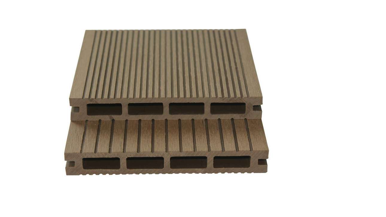 Overhead flat-lay of two stacked tan-brown grooved composite deck boards with hollow channels on a white surface